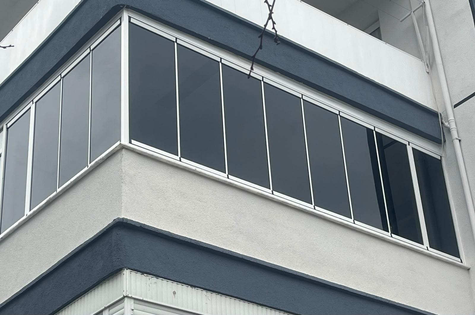 İzmir'de bir apartman cephesine uygulanmış köşe füme cam balkon sistemi